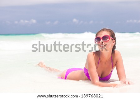 young woman in straw hat and bikini sitting on beach chair