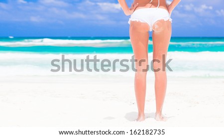 back view of fit young woman in white bikini at beach