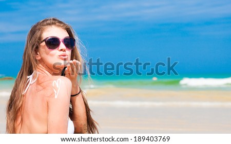 portrait of young woman in sunglasses and straw hat blowing an air kiss on beach