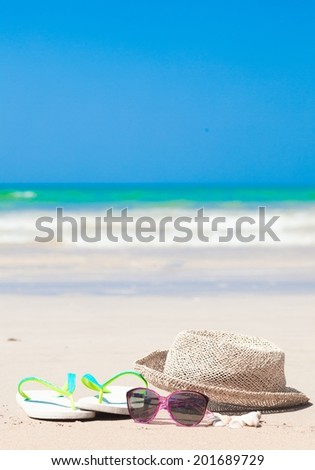sunglasses, flip flops and straw hat on tropical beach