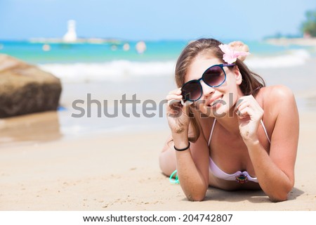 young woman in white bikini lying on white sand beach
