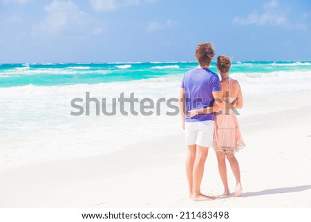 back view of romantic happy young couple hugging at tropical beach