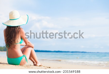 long haired woman in bikini and straw hat bikini on tropical beach