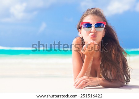 long haired girl in bikini on tropical barbados beach blowing air kiss