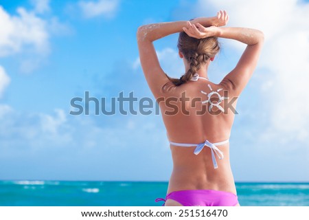 Back View of Woman With Suntan Lotion At The Beach In Form Of The Sun