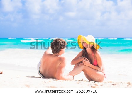 back view of couple sitting on beach