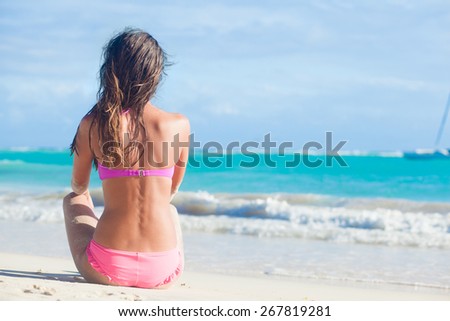 back view of long haired woman in bikini on tropical beach