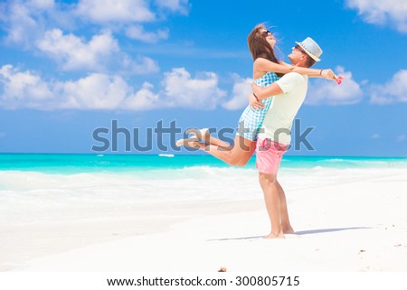 Romantic couple in bright clothes enjoying sunny day at tropical beach