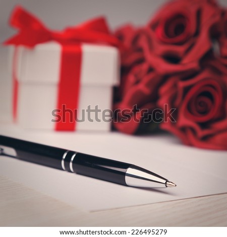 pen with a greeting  card,red roses and white gift box