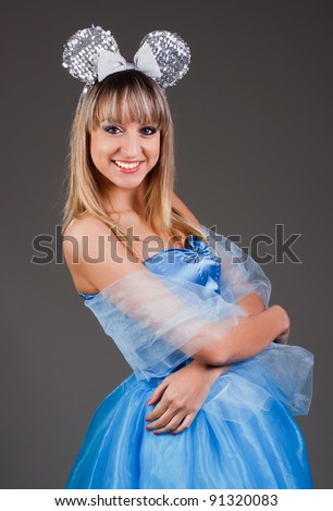 Beautiful girl in a blue dress with a festive mouse ears on a dark gray background