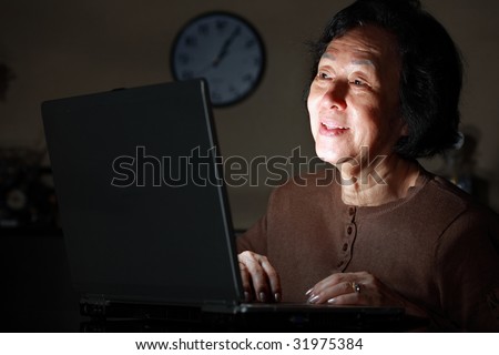 senior asian lady in front of laptop late at night