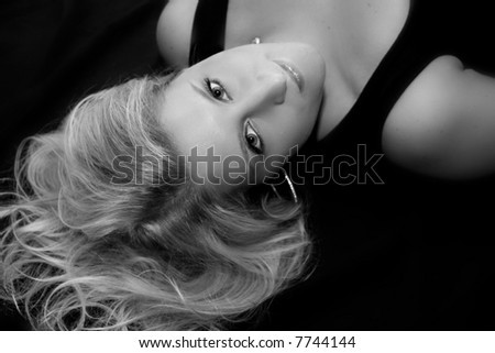 black and white portrait of a beautiful woman lying on black sheets