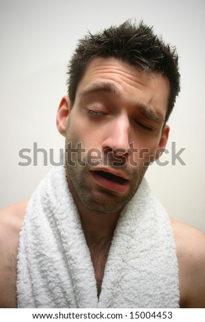 extremely tired young man with white towel in bath room having a bad morning