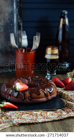 chocolate cake on the base of dark beer with chocolate icing and strawberries - dark rustic style
