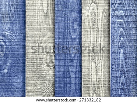 A close up section of  weathered, blue and white striped wooden garden fencing with vertical, overlapped panels.