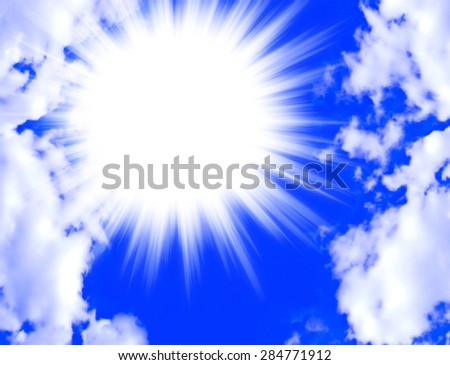 A brilliant star burst of light offset in a bright blue sky framed by fluffy white clouds with copy space