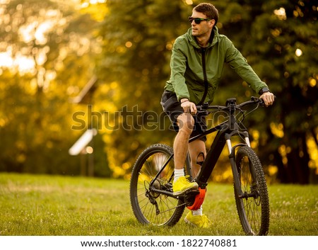 Similar – Image, Stock Photo Young man riding ebike in the park