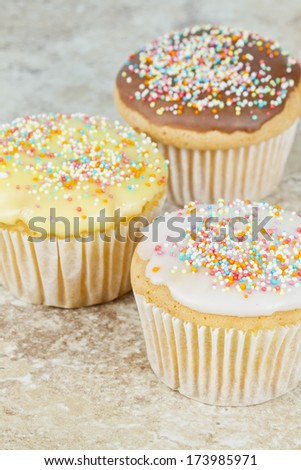 Close-up image of some different flavored cup cakes on a tile background