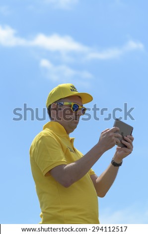 18 June 2015, Clacton-on-sea, Essex, England. UK, a steward  at stage two of the Avive cycling race, looking at a small hand held computer,