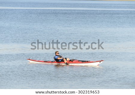 River Stour, Manningtree, Essex, England UK:  30 September 2014- A man floating in his canoe waiting for his friends, on a summers day.