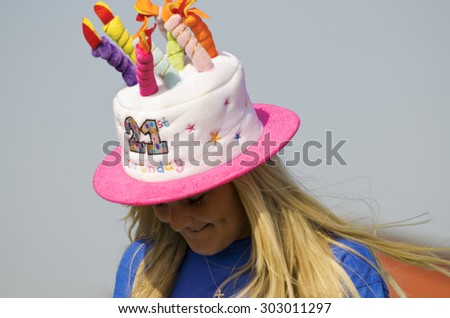 Clacton-on-sea, Essex, England, UK: 15 September 2013- A woman wearing a birthday hat with 21 on with candles on top smiling.