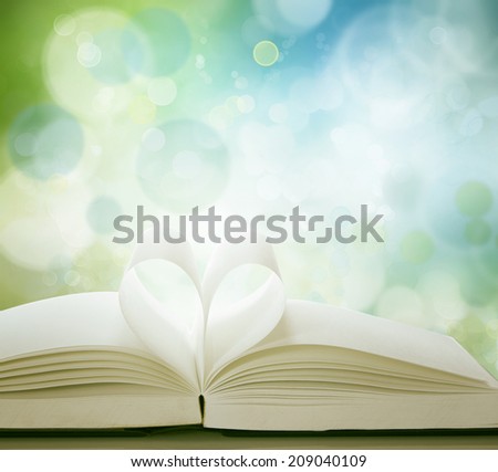 Pages of book in shape of love heart in front of blue green background