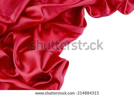 Closeup of folds in red silk fabric on plain background. Copy space