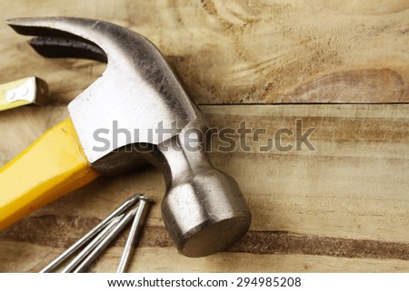 Hammer, nails and tape measure on wood
