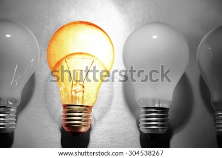 One bright bulb in line of dull light bulbs. Standing out concept