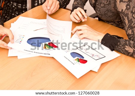 Papers On Desk With Diagrams And Hands Pointing At Growth.
