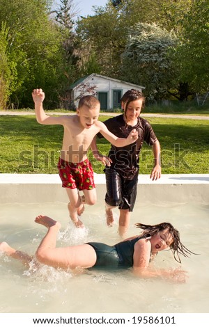 Three young people splash around in a pool on a warm spring day