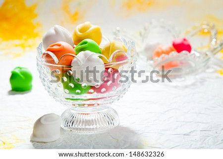 Colorful fondant bonbons in crystal bowl on a white and yellow background