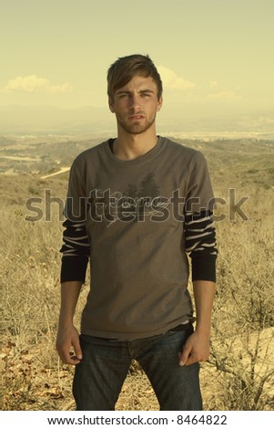 attractive young man standing in a desert field