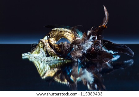 The Venetian mask with feather on a mirror table