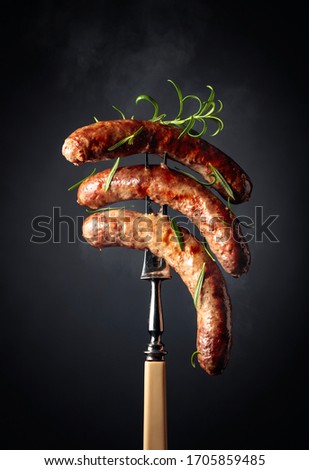Grilled Bavarian sausages with rosemary. Sausages on a fork sprinkled with rosemary.
