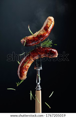 Hot Bavarian sausages with rosemary.  Sausages  on a fork sprinkled with rosemary.