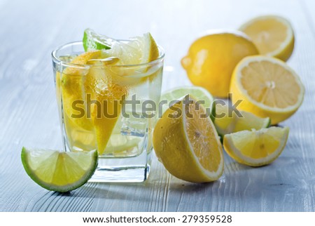 gin and tonic with lemon and ice on wooden table