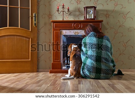 woman in the blanket with  dog near a fireplace
