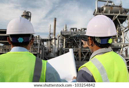 two engineer oil industry discussing a new project with large oil refinery background