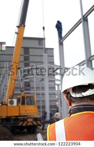 foreman checking plant on construction site with worker background and crane machine