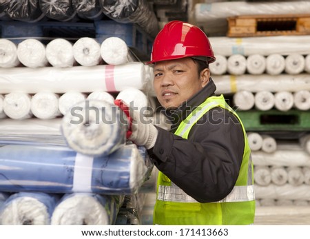 Worker factory textile arranging fabric in warehouse looking at you camera