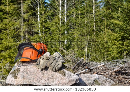 Workers helmet and gloves on a rock in a forest