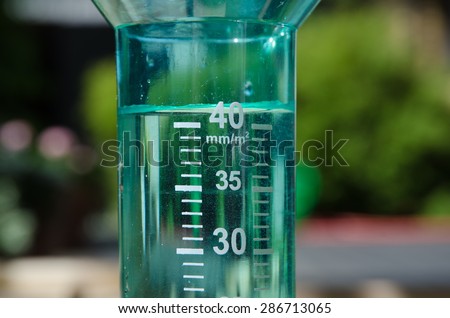 Filled up rain gauge in a garden illustrating a rainy day