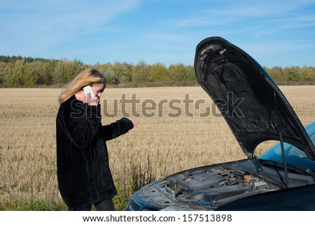image of Beautiful blond girl calling cellphone near her broken car