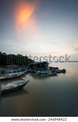 Sunset scene with boats at the beach in portrait format. Slight motion blur due to long exposure.