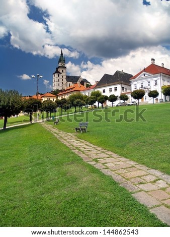 Summer view of freshly cut grass and walkway on main square of Kremnica town with towers of Kremnica castle (Mestsky hrad v Kremnici) in background.