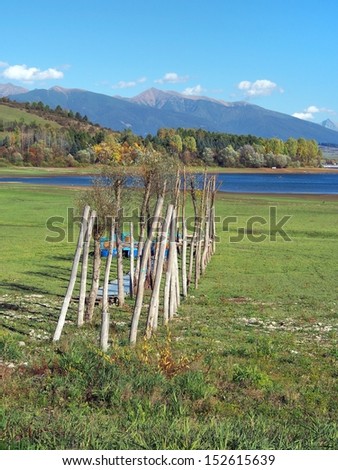 Small wooden pier in autumn, located at Liptovska Mara lake, Slovakia. This is quite rare view because shoreline shown here is dry due low water level at the time when this photo was taken.
