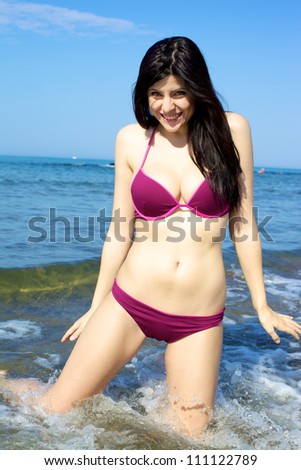 Gorgeous young woman with perfect skin having fun in the ocean on the beach with cold water