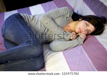 Depressed young woman in bed after domestic violence at home