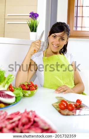 Beautiful female model with knife ready to cut vegetables